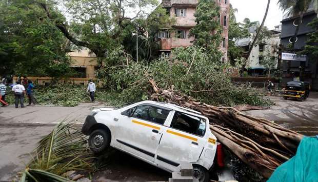 An uprooted tree is seen fallen on a car after strong winds caused by Cyclone Tauktae, in Mumbai, India