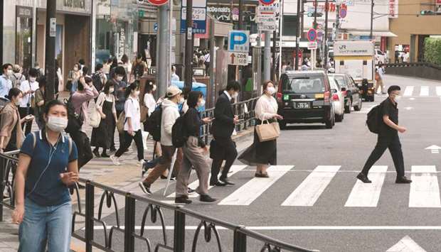 Pedestrians cross a street in Tokyo yesterday. The dismal growth reading and extended state of emergency curbs have heightened the risk Japan may shrink again in the current quarter and slide back to recession, some analysts say.