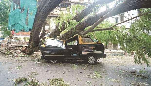A car lies crushed under a fallen tree on a road after heavy winds caused by Cyclone Tauktae, in Mumbai, India, yesterday.