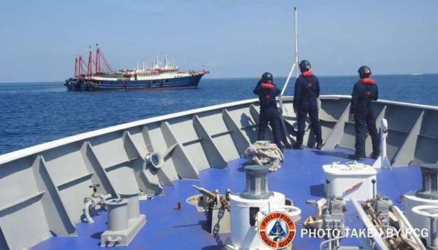 Philippine Coast Guard personnel survey several ships believed to be Chinese militia vessels in Sabina Shoal in the South China Sea