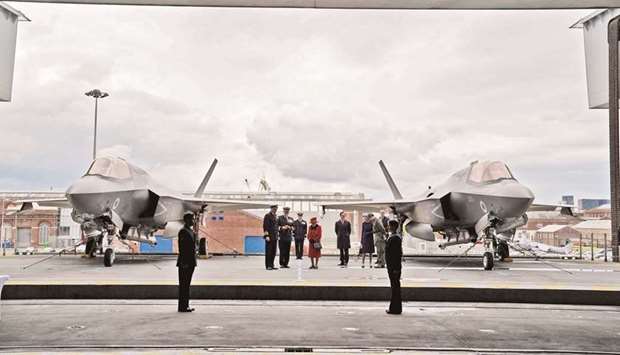 Queen Elizabeth is seen with military personnel between F-35B Lightning II fighter jets on the flight deck of the aircraft carrier HMS Queen Elizabeth in Portsmouth, southern England.