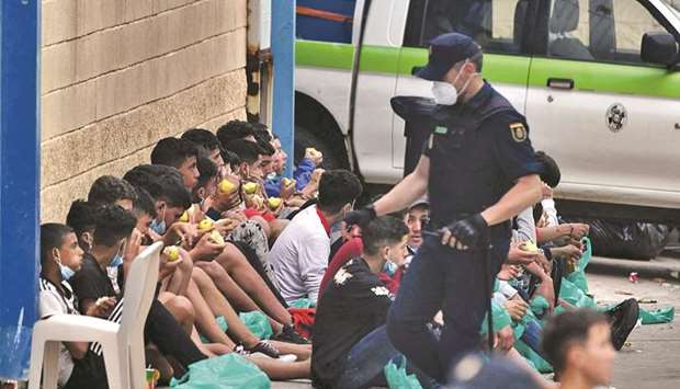 In this file photo taken last Wednesday, migrant minors eat apples while they wait to be tested for Covid-19 upon their arrival to Ceuta. (AFP)