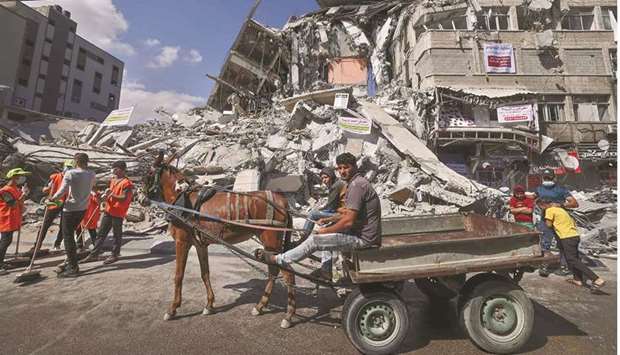 Palestinian volunteers use a donkey-pulled cart to transport rubble as they clean up the streets in the Al-Remal commercial district in Gaza City, recently targeted by Israeli air strikes, yesterday.
