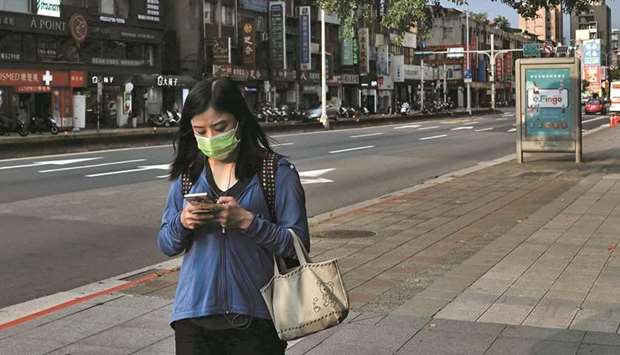 A woman uses her phone while wearing a protective mask following the recent rise in the coronavirus disease infections in Taipei on May 23. The very source of Taiwanu2019s recent geopolitical clout u2014 its dominance of the market for cutting-edge chips u2014 is under attack as governments from the US to Europe and Japan, alerted to the strategic nature of the semiconductor supply chain, seek to spur production at home. China is pumping billions into catching up after Washington imposed export controls on US chip technology.
