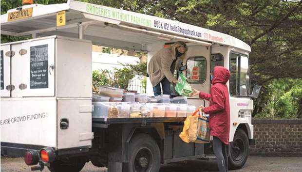 Founder of Topup Truck, Ella Shone (left), serves a customer from her electric milk float (AFP)