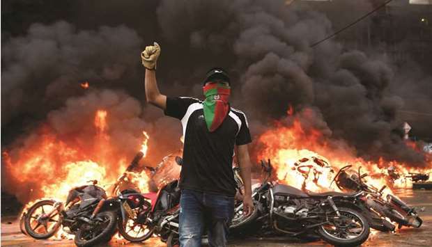 A demonstrator gestures as motorcycles that are impounded for violating traffic regulations are seen on fire at the municipal yards, in Popayan, Colombia. (Reuters)