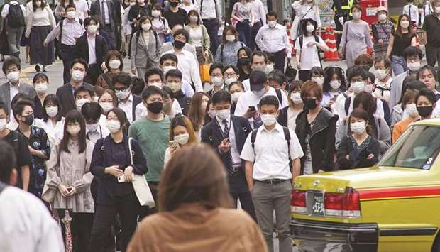 Commuters walk near Shinjuku Station in Tokyo yesterday after the announcement that the government extended a coronavirus emergency in the Japanese capital and other parts of the country until just a month before the Olympics. (AFP)