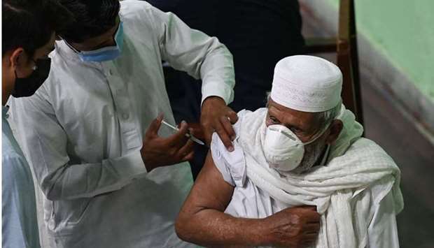A health worker incoluates a man with a dose of the Sinopharm vaccine againsts the Covid-19 coronavirus at a sports complex converted into a vaccination centre, in Rawalpndi