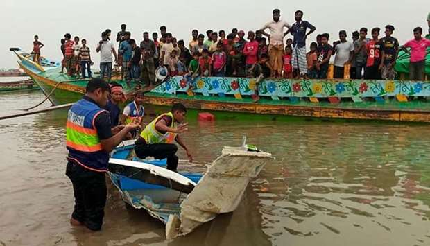 Policemen inspect a speed boat that was carrying passengers when it collided with a vessel transporting sand killing at least 26 people, in Madaripur