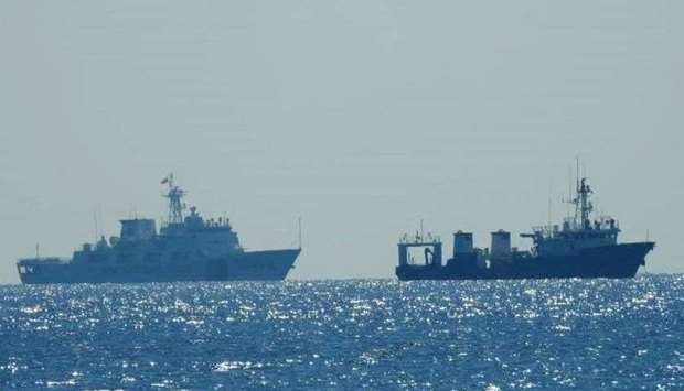 A Chinese Coast Guard patrol ship (L) is seen near an unidentified vessel at South China Sea, in a handout photo distributed by the Philippine Coast Guard April 15 and taken according to the source either on April 13 or 14, 2021. (Reuters)