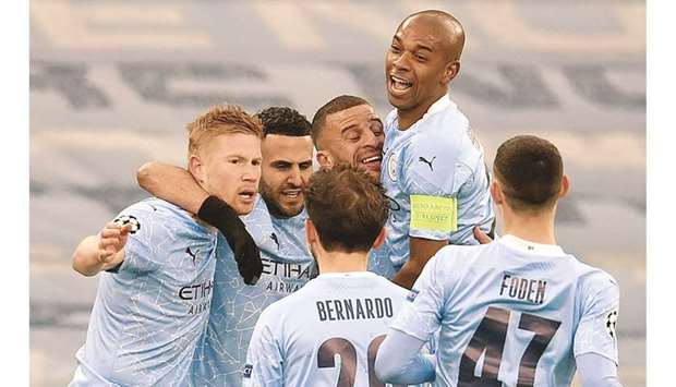 Manchester Cityu2019s Algerian midfielder Riyad Mahrez (2L) is mobbed by teammates after scoring the opening goal against Paris Saint-Germain (PSG) at the Etihad Stadium in Manchester yesterday.