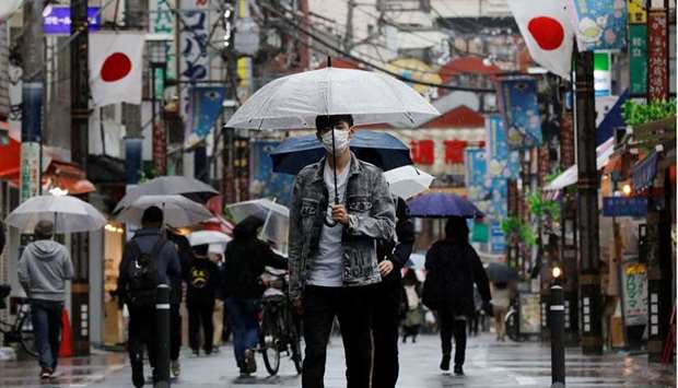 A man wearing a protective face mask, amid the coronavirus disease (Covid-19) pandemic, makes his way at a local shopping street in Tokyo, Japan