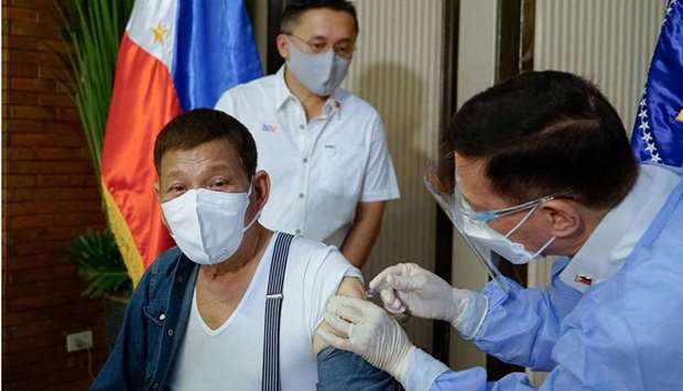 Philippine President Rodrigo Duterte (L) receiving a dose of vaccine against the Covid-19 coronavirus from the Secretary of Health Francisco Duque (R) at Malacanang Palace in Manila.