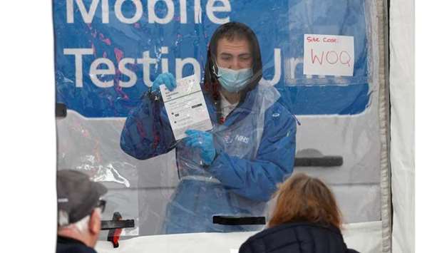 An NHS worker explains the coronavirus disease testing protocol to local residents at a mobile testing unit in Tower Hamlets, London, Britain on May 2. REUTERS