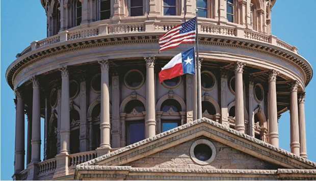 The US flag and the Texas State flag fly over the Texas State Capitol in Austin, Texas, US.