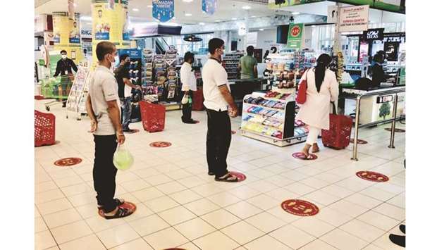 Shoppers maintain social distancing while waiting at the check-out counter of a hypermarket in Doha.