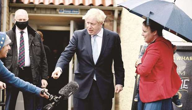 Britainu2019s Prime Minister Boris Johnson jokes with a journalist (left) as he is greeted by a supporter and her son, in Hartlepool, northeast England, yesterday, during a visit following the Conservative Party by-election victory in the constituency.