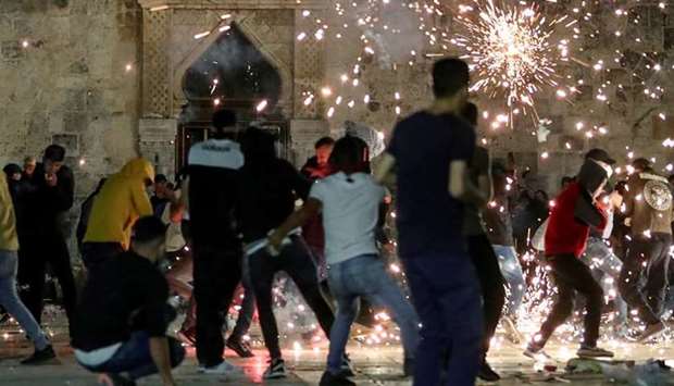 Palestinians react as Israeli police fire stun grenades during clashes at the compound that houses Al-Aqsa Mosque yesterday.