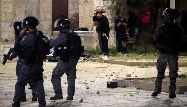 Palestinians take cover during clashes with Israeli police at the compound that houses Al-Aqsa Mosqu