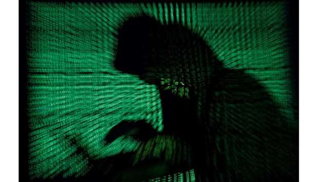 A hooded man holds a laptop computer as cyber code is projected on him in this illustration picture taken on May 13, 2017. Top U.S. fuel pipeline operator Colonial Pipeline has shut its entire network after a cyber attack, the company said on Friday. (REUTERS)
