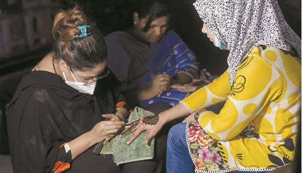 A girl gets her hand decorated with henna paste at a marketplace ahead of the Eid al-Fitr festivities amid the pandemic in Karachi yesterday. (AFP)