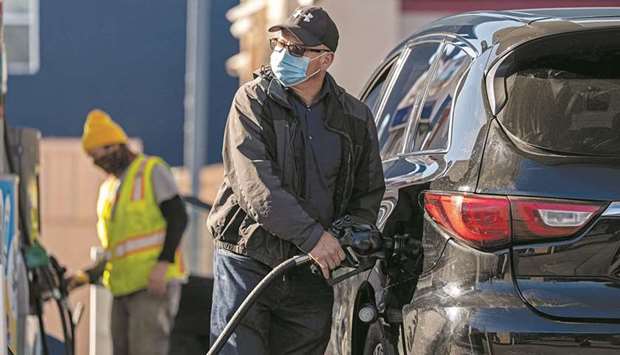A person wearing a protective mask holds a fuel pump nozzle at a Chevron Corp gas station in San Francisco. US gasoline and diesel suppliers are trying to stave off fuel shortages from Atlanta to New York with barges and tankers after a ransomware attack shut down the nationu2019s biggest fuel pipeline.