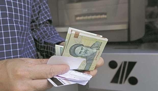 A man withdraws Iranian rial notes from an automated teller machine in the capital Tehran (file). Iran is pushing for its banking industry to be given guaranteed and conclusive sanctions relief at talks to restore the countryu2019s nuclear deal with world powers.
