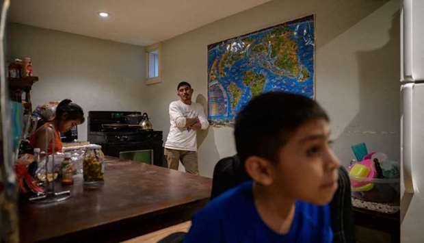 Valeriano (C), 34, an undocumented Guatemalan farmer who entered the US ilegally at the end of March 2021 after being deported following his first attempt, stands in the basement home he shares with his son Arnold (R) and his sister and niece (L) in Hartford, Connecticut on April 29.