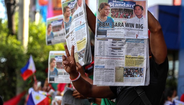 Supporters of Philippine presidential candidate Ferdinand Marcos Jr hold newspapers with coverage of his landslide presidential victory, outside the campaign headquarters in Mandaluyong City, Metro Manila, on May 10, 2022.
