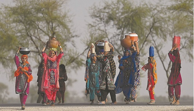 Women carrying drinking water head home during a heatwave in the outskirts of Jacobabad, in Sindh province.