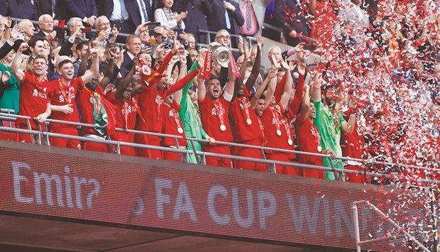 Liverpoolu2019s captain Jordan Henderson lifts the trophy as he celebrates with teammates after winning the FA Cup at the Wembley Stadium in London. (Reuters)