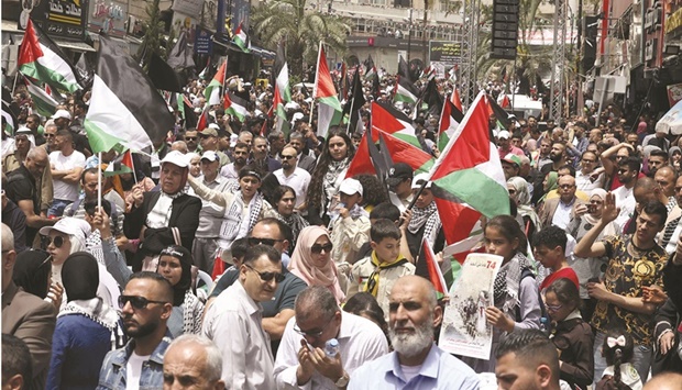 Palestinian wave national flags as they march in a rally marking the 74th anniversary of the u201cNakbau201d or u201ccatastropheu201d, in the occupied West Bank town of Ramallah, yesterday.