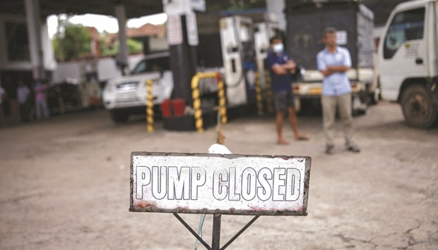 People wait in a queue to buy petrol at a closed fuel station in Colombo yesterday. (Reuters)