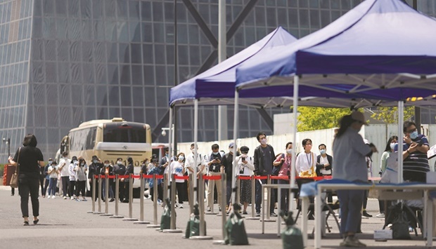 People line up to get tested at a makeshift nucleic acid testing site outside China Central Television headquarters amid the coronavirus disease (Covid-19) outbreak in Beijing. Chinau2019s unrelenting approach to Covid-19 outbreaks has snarled supply chains and locked down tens of millions of people, hitting major financial, industrial and tourist hubs.