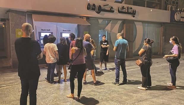 People wait to withdraw money from ATM cash machines in Beirut. Lebanonu2019s local currency has lost more than 90% of its value since its economic decline began in 2019, and banks have locked savers out of hard-currency deposits.