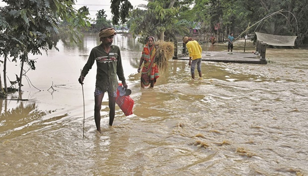Villagers wade through flood waters after heavy rains in Hojai district in Assam.