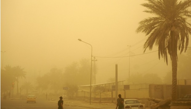 People walk down a road in Iraq's capital Baghdad as thick dust blankets the city. Sabah ARAR / AFP