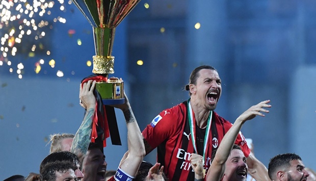 AC Milan's Swedish forward Zlatan Ibrahimovic (Top) and teammates celebrate with the winner's trophy after AC Milan won the Italian Serie A football match between Sassuolo and AC Milan, securing the ,Scudetto, championship on May 22, 2022 at the Mapei - Citta del Tricolore stadium in Sassuolo.
