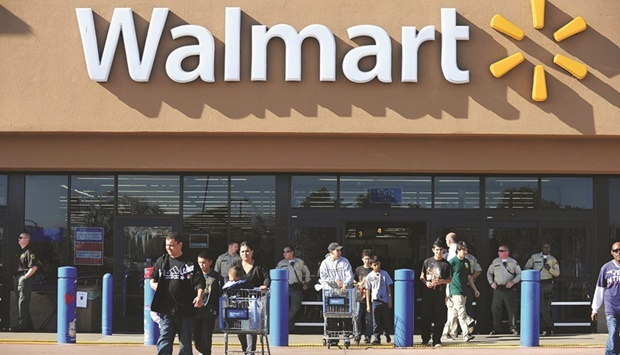 Police patrol the front of a Walmart store as shoppers come and go in Paramount, California (file). Several retailers, including Walmart, have lowered their full-year earnings forecasts, citing high inflation.