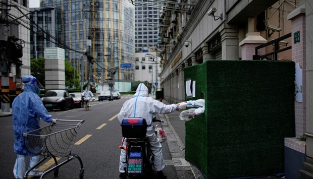 A worker in a protective suit passes food through a gap in the barrier at a residential area during lockdown, amid the coronavirus disease pandemic, in Shanghai, China on May 26. REUTERS