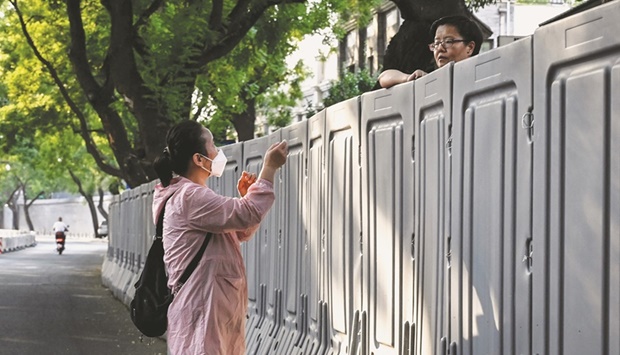 People talk over a barricade at a fenced-off residential area under lockdown due to Covid-19 restrictions in Beijing on Tuesday. The stimulus package, which was flagged by Chinau2019s State Council in a routine meeting last week, underscores Beijingu2019s shift toward growth, after Covid-19 control measures pounded the economy and threaten Beijingu2019s 5.5% growth target for the year.
