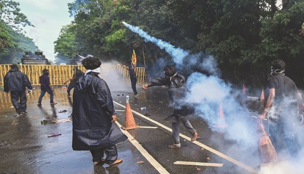 A demonstrator throws back a tear gas canister fired by the police to disperse university students protesting to demand the resignation of Sri Lankau2019s President Gotabaya Rajapaksa over the countryu2019s crippling economic crisis, near the parliament building in Colombo yesterday.