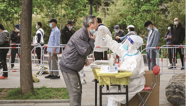 A health worker takes a swab sample from a man to be tested for Covid-19 at a makeshift testing site along a street in Beijing yesterday.