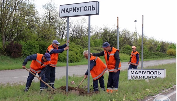 Municipal workers change Ukrainian road signs to Russian outside the city of Mariupol. AFP /Donetsk People Republic Ministry of Transport