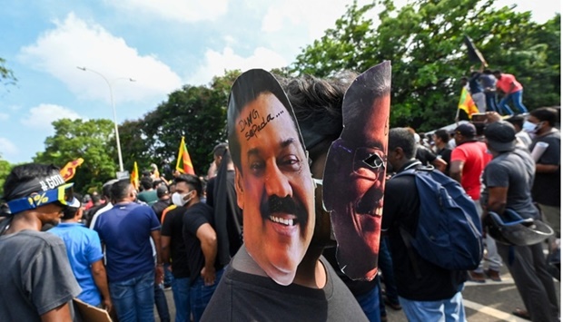 A demonstrator wearing masks of Sri Lanka's President Gotabaya Rajapaksa (R) and Prime Minister Mahinda Rajapaksa takes part in a demonstration with others demanding the resignation of Gotabaya Rajapaksa over the country's crippling economic crisis, near the parliament building in Colombo Friday.