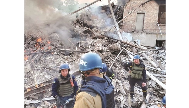 Emergency crew stands near burning debris after a school building was hit as a result of shelling in the village of Bilohorivka, Luhansk, Ukraine. (Reuters)