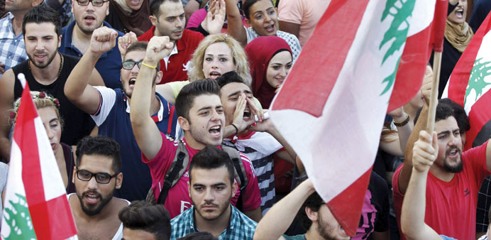 People carry Lebanese national flags and chant slogans as they take part in an anti-government protest at Martyrsu2019 Square in downtown Beirut yesterday