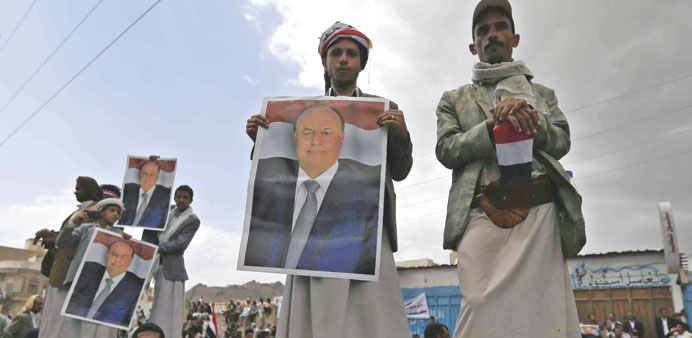 People hold posters of President Abd-Rabbu Mansour Hadi during a pro-government demonstration in Sanaa yesterday.