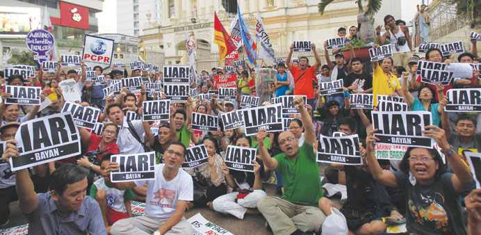 Protesters display placards while watching Philippine President Benigno Aquino address the nation in a live television broadcast, in front of the Cath
