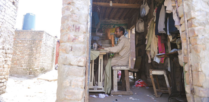 This photograph taken on April 17, 2014 shows Pakistani tailor Akram Mashi making dresses at his shop in the slums of Islamabad.
